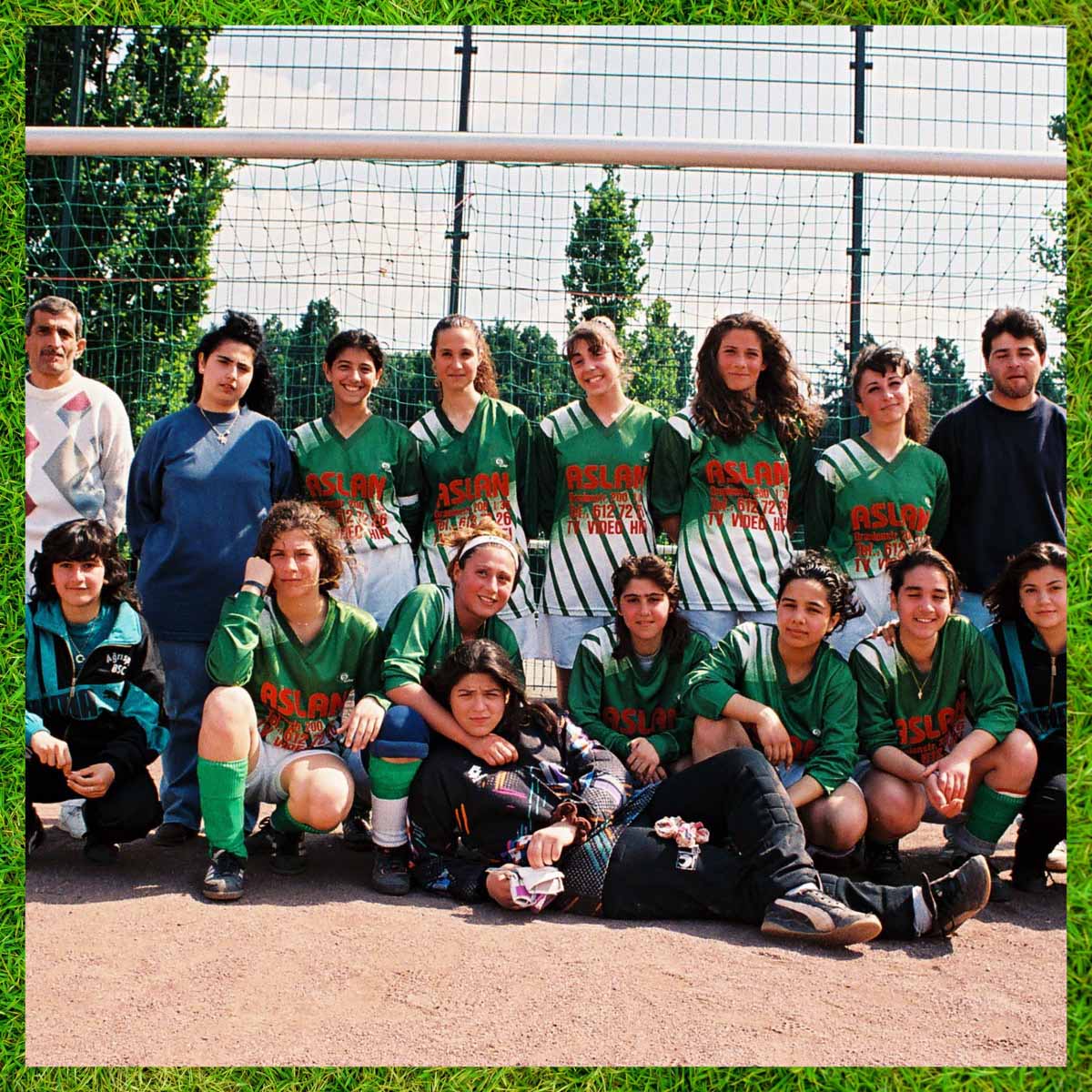 Mannschaftsbild der Mädchen des BSC Agrisport vor einem Fußballtor. Die hintere Reihe steht, eingerahmt von zwei Männern, die vordere Reihe kniet und die Torfrau liegt vor der ersten Reihe und wird von einer Mitspielerin umarmt. Fast alle tragen die grün-weißen Trikots ihres Vereins und schauen zur Kamera. Um das Bild gibt es einen Rahmen, der grünen Fußballrasen zeigt als Symbol für den Fußball-Fokus von Pop-Kultur.